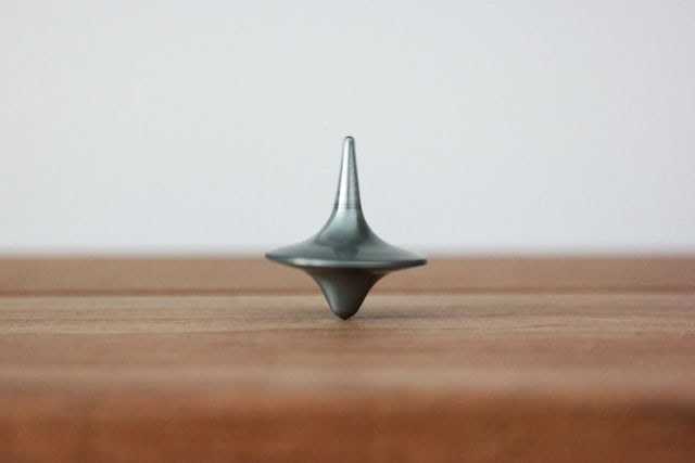 Peonza equilibrada sobre una superficie de madera representando equilibrio, precisión y criterio en la toma de decisiones en clínica dental.